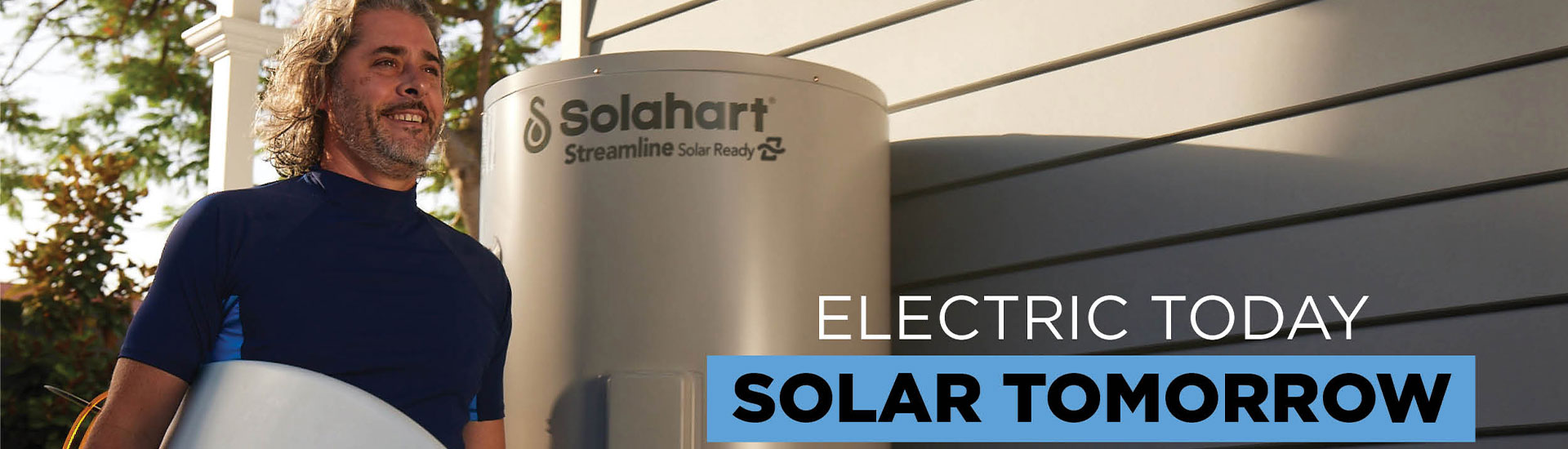 Surfer walking past a Solahart solar ready hot water system
